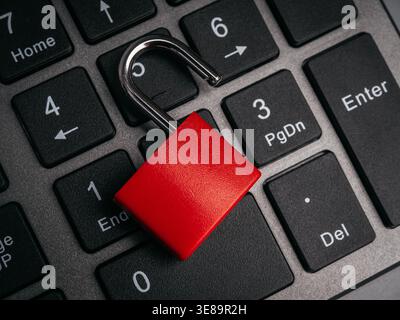 Cybersecurity concept showing unlocked red padlock on computer keyboard numbers background. System hacked, data breach, security vulnerability, and di Stock Photo