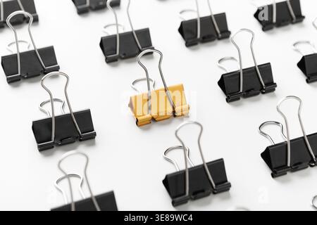 Collection of Black and Yellow Binder Clips Arranged in a Pattern on a White Surface Stock Photo