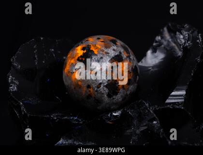 Artistic close up of a patterned marble orb on dark volcanic rock for luxury design or wellness Stock Photo