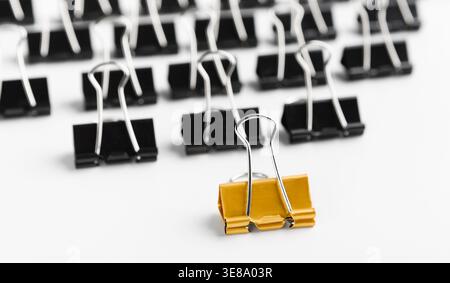 Collection of Black and Yellow Binder Clips Arranged on a Plain White Background Stock Photo