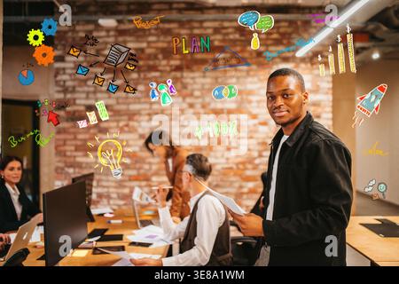 People collaborating in an office with colorful graphics on the wall during a planning session in the afternoon Stock Photo