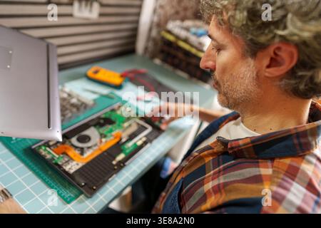 Technician repairing laptop computer, diagnosing electronic circuit board, performing maintenance, IT support service Stock Photo