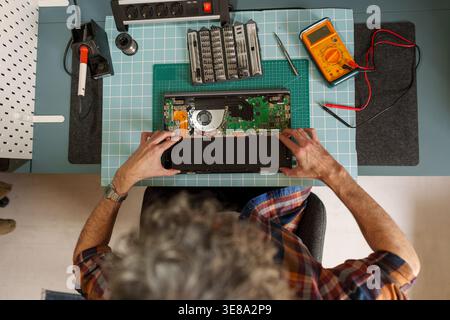 Person working on laptop components, performing diagnosis and repair service. Computer hardware technician fixing motherboard Stock Photo
