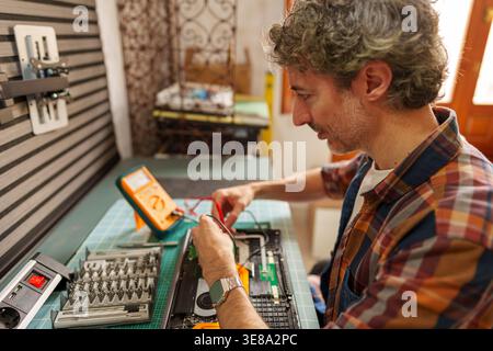 Man repairing laptop computer, diagnosing electronic circuit using a multimeter, professional technician fixing modern technology Stock Photo