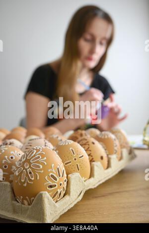 Woman painting pysanka eggs, celebrating easter holiday with folk art tradition. Stock Photo
