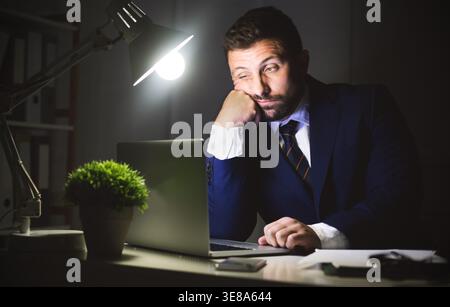 Overwork. Businessman working on laptop in office Stock Photo