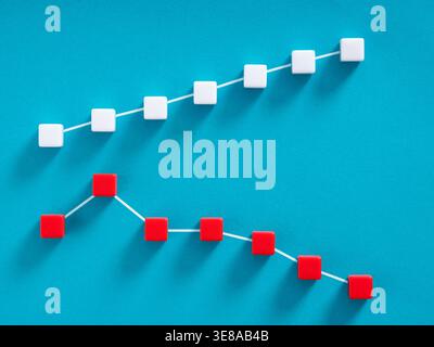 Rising white line graph and falling red line graph on blue background, concept of stock market volatility, profit and loss or business performance com Stock Photo