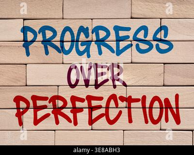 Words PROGRESS OVER PERFECTION written on a wall of wooden toy blocks Stock Photo