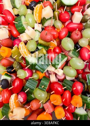 Top view of assorted canapes with vegetables, fruits, cheese and sausages on wooden skewers, party food and appetizer Stock Photo