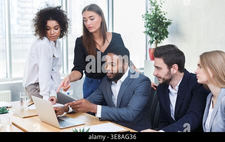 Business managers analyzing data on laptop at meeting Stock Photo