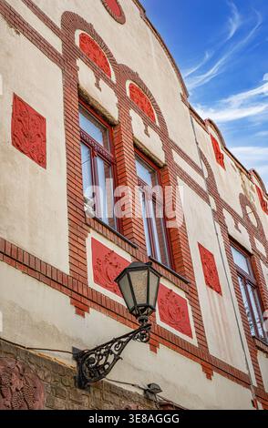A vintage European building featuring cream-colored walls, red brick accents, and a classic black wrought-iron lantern. Stock Photo