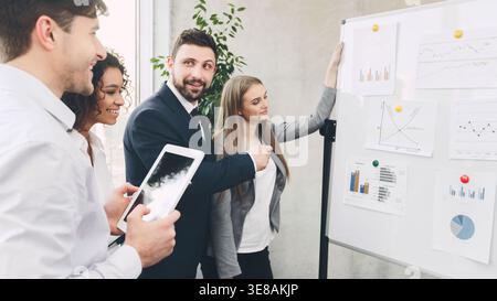 Young business colleagues discussing over charts on board Stock Photo