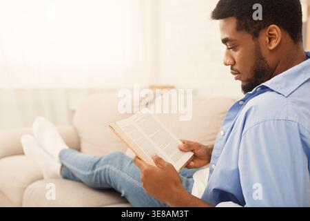 Black male student reading book at home Stock Photo