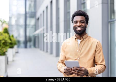 Confident young adult african entrepreneur using a digital tablet, representing professionalism, success, and innovation in a modern business environment Stock Photo