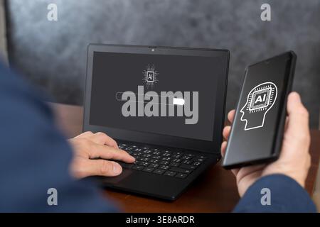 Close-up of a user operating a laptop while holding a smartphone, both showing AI-themed screens, visualizing setup progress, device synchronization, Stock Photo