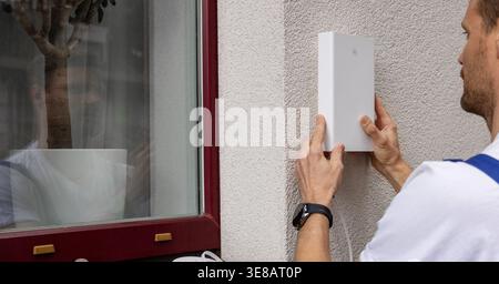 service provider technician installing 5G router antenna on house exterior. fast internet at home Stock Photo