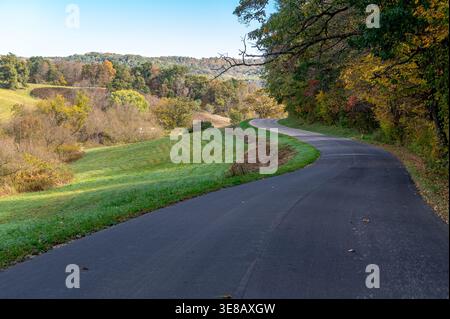 Winding rural road through the Driftless Area of Wisconsin, showcasing rolling hills and scenic countryside in the early autumn. Stock Photo