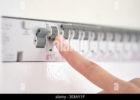 Hand switching circuit breaker in electrical distribution panel. Concept of power control, electrical safety, household utility and energy management. Stock Photo