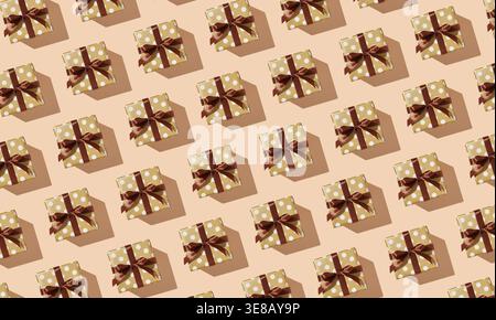 Pattern of many gift boxes with polka dots and brown ribbons on a beige background. Stock Photo