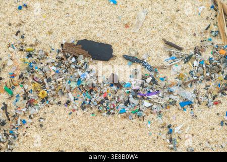 Close up of microplastic fragments mixed with sand on tropical beach on Phuket island, Thailand. Garbage and trash on polluted beach. Environmental Stock Photo