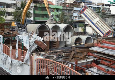 Bangkok, thailand - Apr 04, 2022 : At a cluttered urban construction site, several large-diameter concrete drainage pipes are stacked alongside a vari Stock Photo