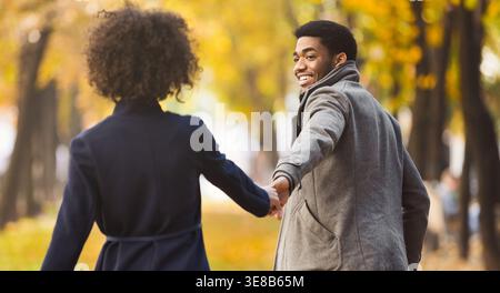 Follow me. Happy couple walking in autumn city park Stock Photo