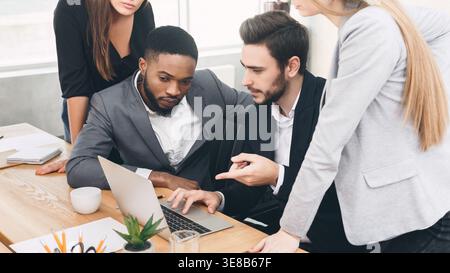 Analyzing fresh data. Serious business team looking at laptop Stock Photo