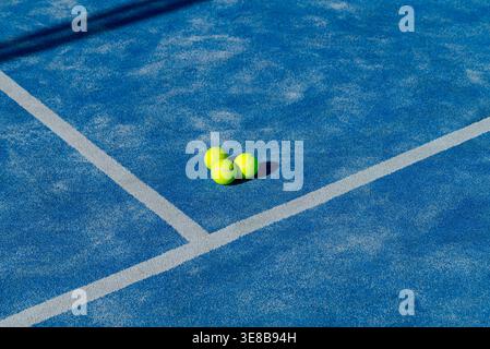 Padel game equipment featuring three balls prominently displayed on a textured blue surface. Stock Photo