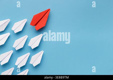 Collage of Paper Airplanes on Blue, With a Red Plane Leading the Group Stock Photo