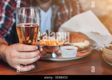 Man having rest, drinking beer and eating burger in pab Stock Photo