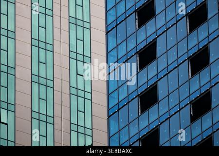 Close up of modern architecture facade featuring contrasting glass panels and concrete structure. Geometric composition with repeating windows in blue Stock Photo
