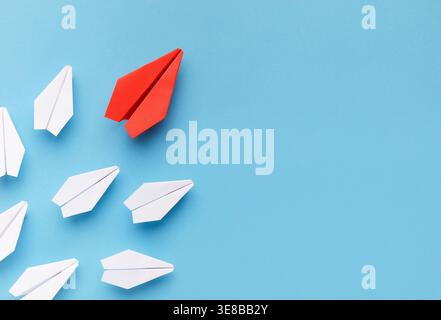 Collage of Paper Airplanes in Different Colors on a Blue Background With Focus on One Red Airplane Stock Photo