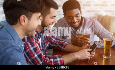 Best friends using smartphone and drinking beer Stock Photo