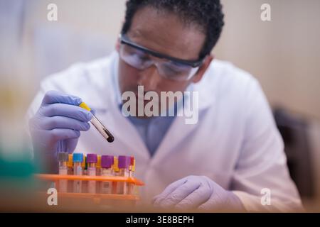 Lab technician carefully handling blood test sample in clinical laboratory wearing gloves and goggles Stock Photo
