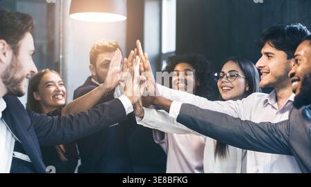 Happy office workers giving high five at meeting Stock Photo