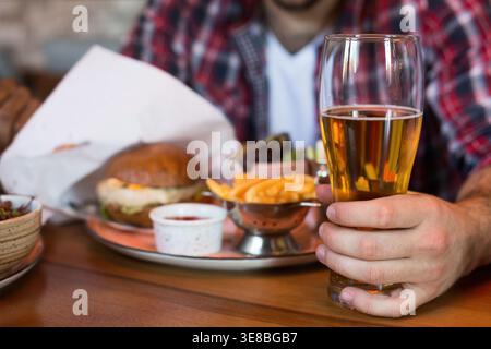 Man drinking beer and eating burger in pab Stock Photo