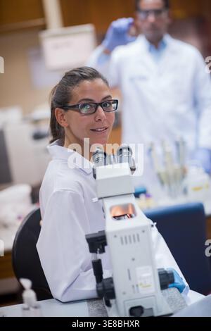 Young lab technician and doctor collaborating on blood testing using a microscope in a clinical laboratory Stock Photo