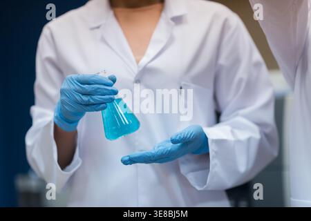 Middle Eastern doctors and medical technician handling blue liquid in blood testing laboratory Stock Photo