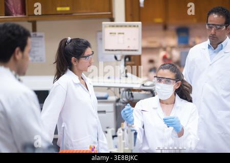 Middle Eastern medical team performing blood testing in a clinical laboratory with protective gear and teamwork Stock Photo