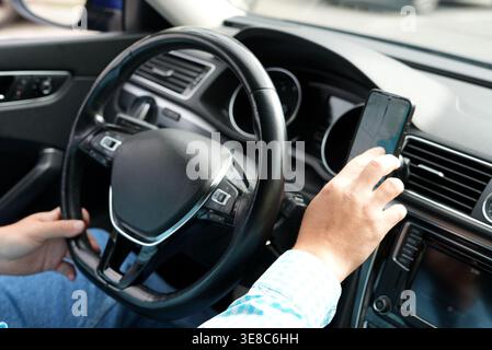Driver using smartphone navigation while driving car interior Stock Photo