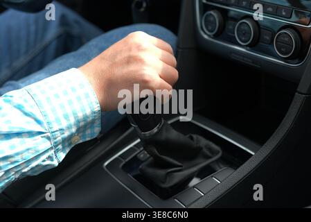 Hand shifting manual gear stick in car close up driver control Stock Photo