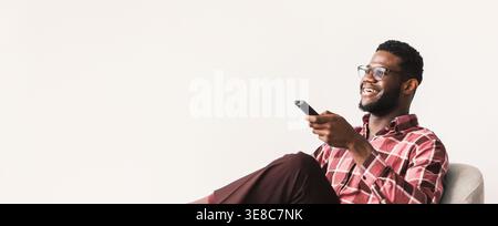 Man Sitting on Sofa and Watching Television While Holding Remote Control in Hand Stock Photo