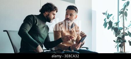Two Men Discuss Ideas While Seated in a Modern Office Space During the Afternoon Stock Photo