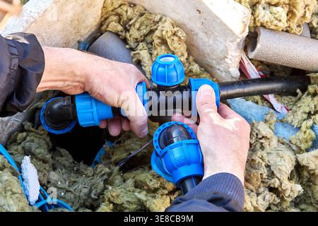 Compression tee fitting for HDPE pipes in hands of plumber. Stock Photo
