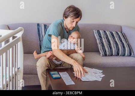 Father sitting on sofa holding baby while calculating monthly expenses with receipts at home. Stressed dad managing budget and childcare. Financial Stock Photo