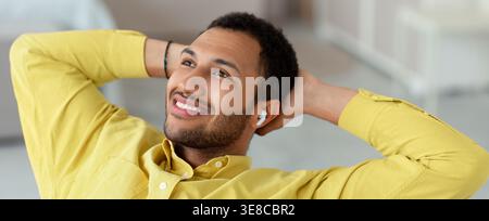Young Man Relaxing With Earbuds in a Bright Indoor Space During the Day Stock Photo