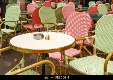 Parisian cafe terrace featuring colorful wicker style chairs and small tables, creating an inviting outdoor dining atmosphere Stock Photo
