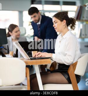 Young woman works on laptop with colleagues Stock Photo