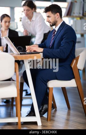 Focused young man working on laptop during busy corporate session Stock Photo