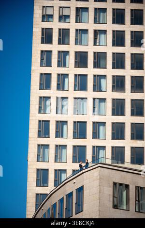 Two businessmen on terrace dwarfed by tower facade, Berlin, Germany Stock Photo